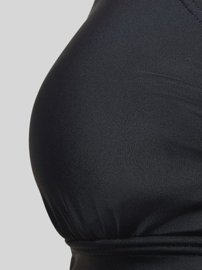 Frauenmodel trägt Bikini-Top mit Cut-Out Modell 'Lolo' von LASCANA aus elastischem Materialmix in Schwarz, Nahaufnahme Oberkörper.