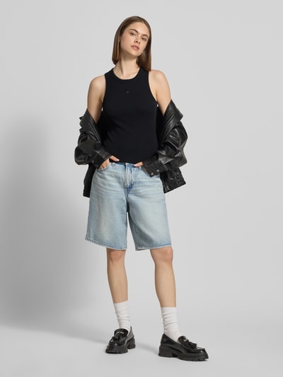 Frauenmodel trägt Tanktop in Ripp-Optik Modell 'Philips' von Carhartt Work In Progress aus Baumwoll-Elasthan-Mix, Slim-Fit, Rundhalsausschnitt, helle Jeansshorts, schwarze Schuhe, schwarze Jacke, Ganzkörperansicht von vorne.
