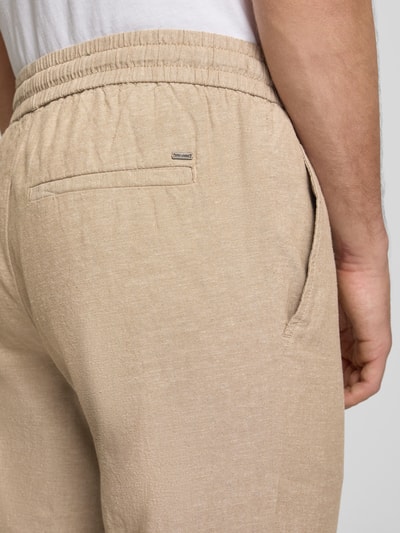 Männermodel trägt Tapered Leinenhose aus Baumwoll-Leinen-Mix Modell 'LINUS' von Only & Sons in Melange-Optik mit seitlichen Eingrifftaschen, Tunnelzug und elastischem Bundabschluss, Nahaufnahme Rückansicht.