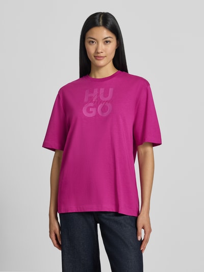 Frauenmodel trägt Oversized T-Shirt aus reiner Baumwolle Modell 'Dashire_5' von HUGO in kräftigem Pink, grafischer Print, Damen T-Shirt, Ganzkörperansicht von vorne.