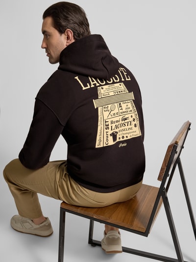 Männermodel trägt Regular Fit Hoodie aus reiner Baumwolle von Lacoste, Optik: Unifarben, Motiv-Print, Sweat, Ganzkörperansicht Rückansicht.