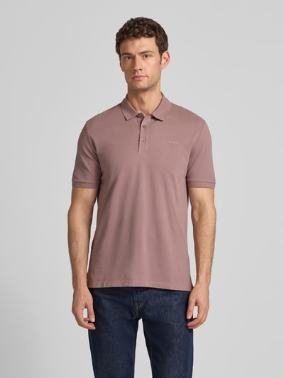 Männermodel trägt Regular Fit Poloshirt aus reiner Baumwolle Modell 'DONOS222' van HUGO, uni, label print, polokraag, piqué, Ganzkörperansicht von vorne.