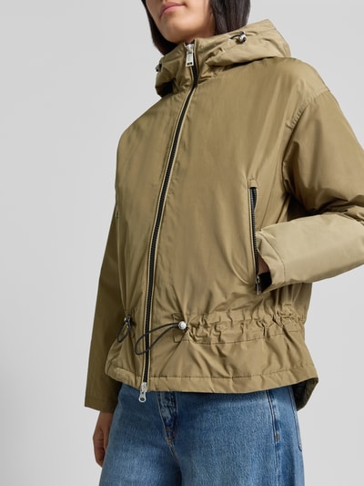 Vrouwenmodel draagt Regular Fit jack met katoenmix van FUCHS SCHMITT in olijfgroen, tweewegritssluiting, tunnelkoord capuchon, Materiaalmix, Ruglengte bij maat 36: 64 cm, Schouderbreedte 53 cm, Borstwijdte 55 cm, Mouwlengte 56 cm, Nahaufnahme bovenlichaam.