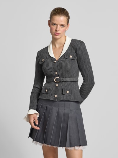 Vrouwenmodel draagt cardigan met viscose-wol-aandeel van Self-Portrait, materiaalmix, slim fit, tricotlook, klepzakken, met lange mouwen, ruglengte bij maat S 57 cm, grijze en witte tinten, fijngebreide textuur, geheellichaamsaanzicht van voren.