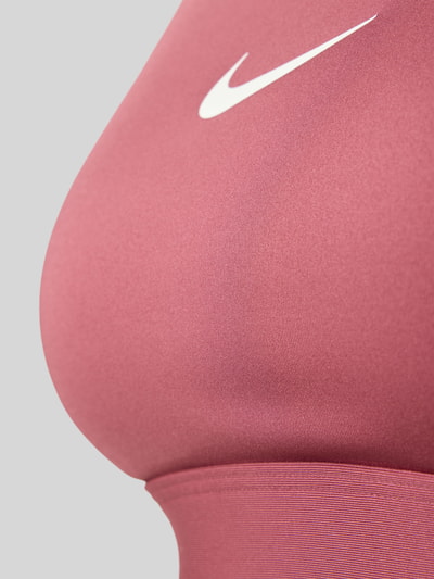 Mädchen trägt Sport-BH mit Logo-Print von Nike in Altrosa mit glatter Textur, Nahaufnahme Oberkörper, Damen Sport-BH von Nike