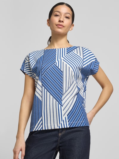 Frauenmodel trägt Regular Fit T-Shirt mit Allover-Muster von s.Oliver RED LABEL in Blau-Weiß mit U-Boot-Ausschnitt aus Musselin, Nahaufnahme Oberkörper.