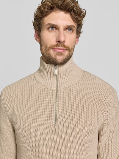 Männermodel trägt Slim Fit Strickpullover aus reiner Baumwolle mit Troyer-Kragen von MCNEAL, beige, gerippte Textur, Nahaufnahme Oberkörper.