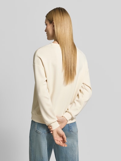 Männermodel trägt Regular Fit Sweatshirt mit Ziersteinbesatz Modell 'Banu' von Soyaconcept, kremowy kolor, materiał elastyczny z modalu, okrągły dekolt, elastyczne wykończenia, krój regular fit, widok całej sylwetki z tyłu