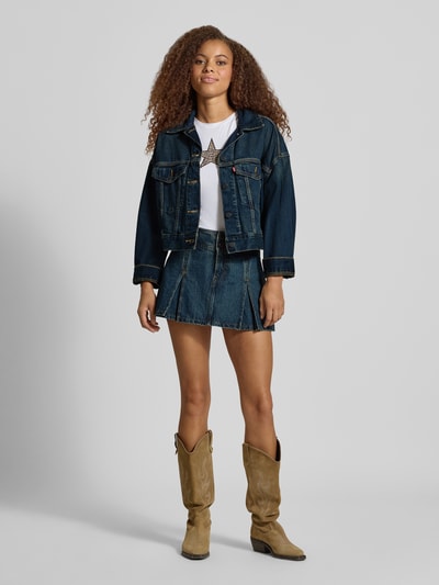 Frauenmodel trägt Jeansjacke mit Label-Detail Modell 'LOOSE CROP TRUCKER' von Levi's® 300, dunkles Denim, silberne Knöpfe, Ganzkörperansicht von vorne.
