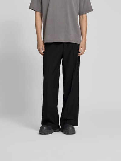 Männermodel trägt Wide Fit Leinenhose mit Gesäßtaschen von WON HUNDRED in Schwarz, elastischer Leinen-Mix mit Bügelfalten, Ganzkörperansicht von vorne.