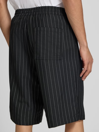 Mężczyzna nosi szorty z elastycznym pasem model 'CRISTIANO' od Redefined Rebel, mieszanka materiałów z dodatkiem streczu, krój relaxed fit, szerokość w rozmiarze M: 42 cm, długość wewnętrzna nogawki: 27 cm, widok tyłu w ujęciu całopostaciowym.