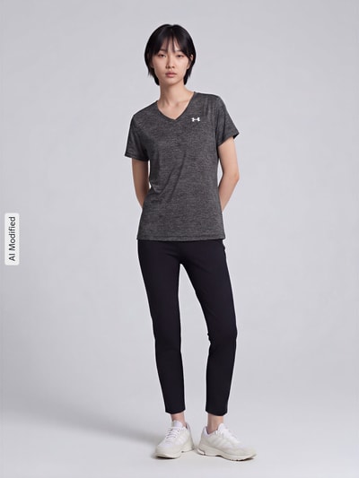 Frauenmodel trägt Regular Fit Sport-T-Shirt mit LOGO-Print Modell 'Tech SSV- Twist' von Under Armour in Dunkelgrau zu schwarzer Hose, Damen Sport-T-Shirt von Under Armour, Ganzkörperansicht von vorne.