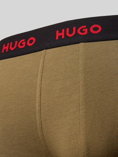 Männermodel trägt Trunks aus Baumwoll-Mix mit elastischem Label-Bund im 3er-Pack von HUGO, unifarben, Nahaufnahme Hüfte.