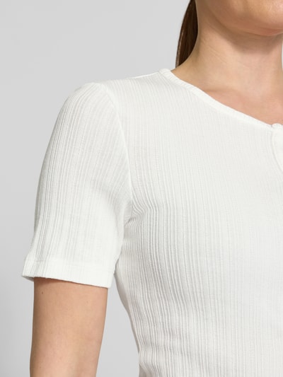 Frauenmodel trägt Strickshirt mit Knopfleiste Modell 'SAJUNI' von Samsøe Samsøe aus Reine Baumwolle, Regular-Fit, Motiv-Print, Rundhalsausschnitt, Nahaufnahme Oberkörper.