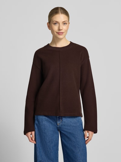 Frauenmodel trägt Relaxed Fit Sweatshirt aus Baumwoll-Mix von s.Oliver RED LABEL in Dunkelbraun, kombiniert mit blauer Jeans, Ganzkörperansicht von vorne.