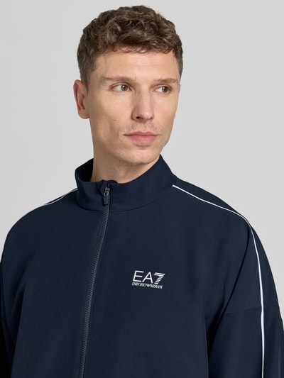 Männermodel trägt Bomberjacke mit Stehkragen und Logo-Print von EA7 Emporio Armani, dunkelblau, VENTUS7-Gewebe, Nahaufnahme Oberkörper.