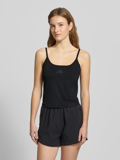 Frauenmodel trägt schwarzes Tanktop mit Label-Print von adidas Sportswear, Slim Fit, glatte Textur, Ganzkörperansicht von vorne.