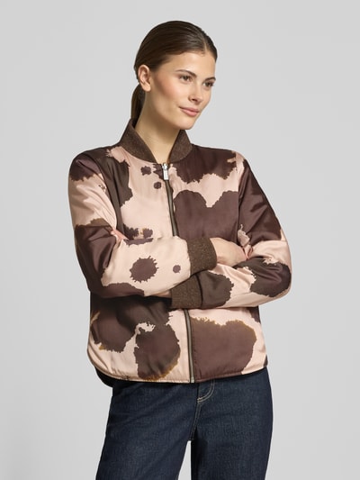 Vrouwenmodel draagt Regular Fit bomberjack met opstaande kraag van Scotch & Soda in bruin-beige tinten, steekzakken, ritssluiting, elastische boorden, ruglengte maat S 57 cm, schouderbreedte 36 cm, borstwijdte 48 cm, mouwlengte 62 cm. Ganzekörperaanzicht van voren.