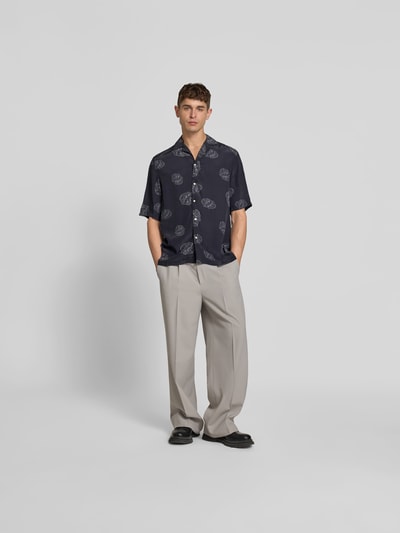 Männermodel trägt Relaxed Fit Langarmbluse aus Viskose von Officine Générale in Dunkelblau mit Muster, Reverskragen, lockerer Schnitt, Ganzkörperansicht von vorne.