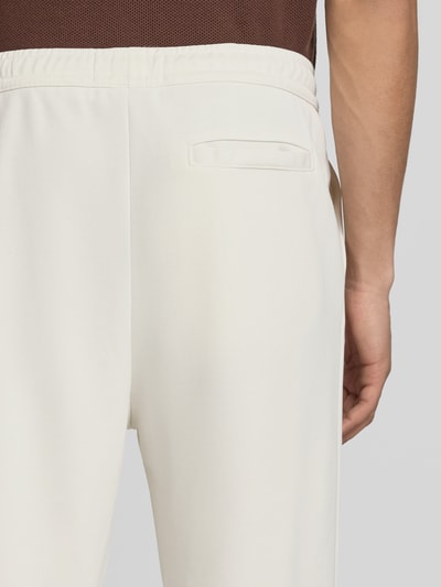 Männermodel trägt Trackpants mit Längsnähten Modell 'Motus' von Pegador, Material-Mix mit Baumwoll-Anteil, Relaxed-Fit, Detailaufnahme Rückansicht.