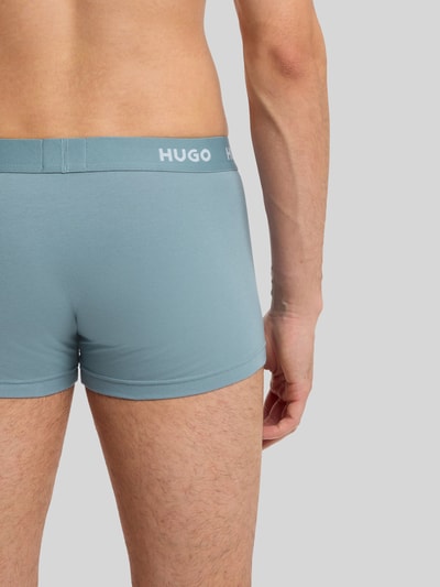 Männermodel trägt Slim Fit Trunks aus Baumwoll-Mix im 3er-Pack Modell 'PACK' von HUGO, Optik: Unifarben, Nahaufnahme Rückansicht.