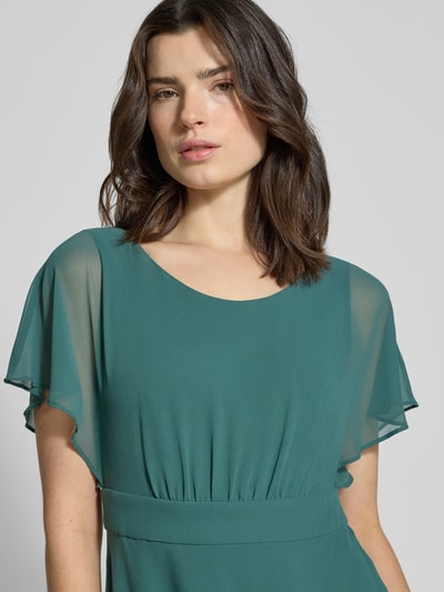 Frauenmodel trägt Knielanges Kleid mit Rundhalsausschnitt von Vera Mont, smaragdgrün, semitransparent, tailliert, Nahaufnahme Oberkörper.