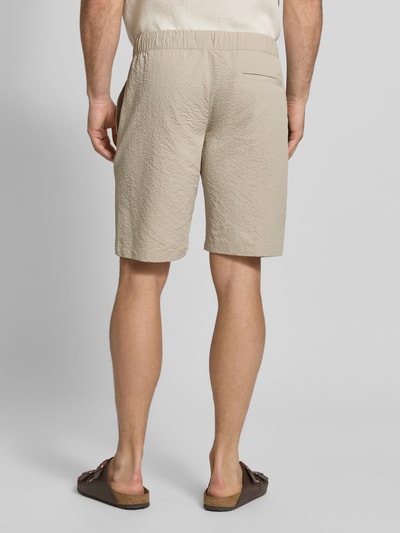 Männermodel trägt Shorts mit elastischem Bund und Eingrifftaschen von MCNEAL, sandfarben, Strukturmuster, Regular-Fit, Ganzkörperansicht Rückansicht.