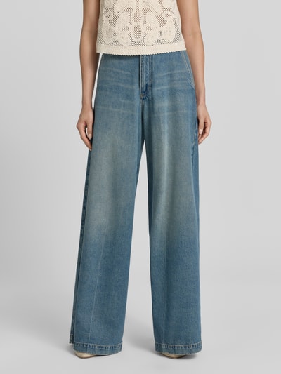Frauenmodel trägt Regular Fit Baggy Jeans aus Baumwoll-Lyocell-Mix Modell 'CENTRAL' von BOSS in Denim-Optik mit 5-Pocket-Design, Label Patch, Knopf und verdecktem Reißverschluss, mittlere Waschung, ganzkörperansicht von vorne.