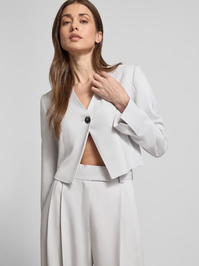 Frauenmodel trägt Weite Anzughose mit hoher Taille - curated by Vicky Heiler von SIC, Viskose-Elasthan-Mix, Wide Leg, Bügelfalten, Pattentaschen, Bundweite 35 cm, Innenbeinlänge 83 cm, helle Farbe, glatte Textur, Nahaufnahme Oberkörper.