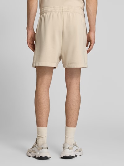 Mężczyzna nosi Regular Fit Sweatshorts mit Modal und Baumwoll-Anteil von adidas Sportswear, efekt: jednolity kolor, krój regular fit, detal z logo, elastyczny ściągacz z tunelem, wpuszczane kieszenie, mieszanka materiałów z modalu i bawełny, Ganzkörperansicht Rückansicht.