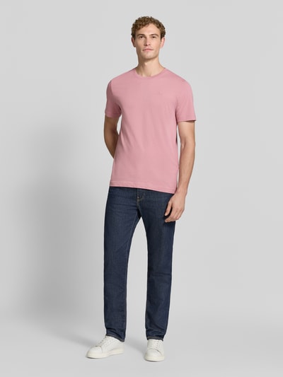 Männermodel trägt Regular Fit T-Shirt aus reiner Baumwolle von Tom Tailor in Rosa, kombiniert mit Jeans, Ganzkörperansicht von vorne. Herren T-Shirt von Tom Tailor.