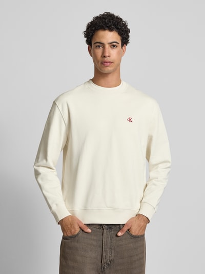 Męski model nosi Sweatshirt aus reiner Baumwolle od Calvin Klein Jeans, kremowy kolor, prosty krój, okrągły dekolt, przód, ujęcie całej sylwetki.