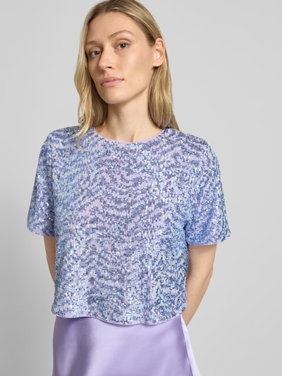 Vrouwenmodel draagt Cropped T-shirt met pailletten model 'Dine' van GUIDO MARIA KRETSCHMER WOMAN, materiaalmix met stretch, ronde hals, ruglengte maat 36: 39 cm, geheel in lila-blauw tinten, glanzende textuur, nahaufnahme bovenlichaam.