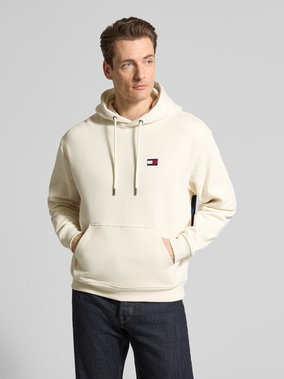 Männermodel trägt Regular Fit Hoodie aus reiner Baumwolle von Tommy Hilfiger in Unifarben mit Logo-Applikation, Kängurutasche, Ganzkörperansicht von vorne.