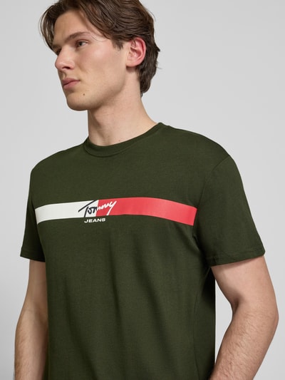 Männermodel trägt Regular Fit T-Shirt aus reiner Baumwolle von Tommy Jeans in Optik: Unifarben, Label-Print, Nahaufnahme Oberkörper.