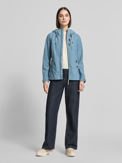 Vrouwenmodel draagt lichtblauwe dames jack met capuchon, ritssluiting, ritszakken, slim fit, model 'GS111' van G.I.G.A. DX, ruglengte 69 cm, schouderbreedte 39 cm, borstwijdte 44 cm, mouwlengte 65 cm, waterdicht tot 10.000 mm waterkolom. Volledige lichaamsweergave van voren.