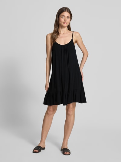 Frauenmodel trägt Minikleid aus Viskose mit tiefem Rückenausschnitt von Shiwi, Schwarz, A-Linie, Modell 'Ibiza Dress Solid', Ganzkörperansicht von vorne.