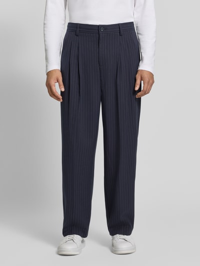Männermodel trägt Stoffhose mit Bügelfalte Modell 'GRANT' von Casual Friday, dunkelblauer Stoff mit feinen Nadelstreifen, Ganzkörperansicht von vorne. Material-Mix mit Viskose-Anteil, Straight Fit, Knopf- und Reißverschluss, französische Eingrifftaschen, Gesäßleistentaschen.