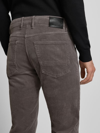 Mężczyzna nosi Modern Fit Spodnie materiałowe z 5 kieszeniami od Bugatti z mieszanki bawełny i elastanu, szara tekstura, detal z tyłu, zapięcie na guzik i zamek błyskawiczny, długość nogawki 82 cm, szerokość pasa 44 cm, Ganzkörperansicht Rückansicht.
