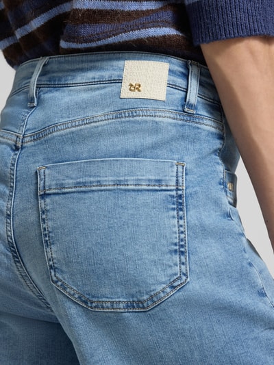 Kobieta nosi jeansy w stylu wide fit model 'MIRU' od Raffaello Rossi, jasnoniebieski denim, nakładane kieszenie, długość 6/8, Szerokość w rozmiarze 36: 41 cm, długość wewnętrzna nogawki w rozmiarze 36: 71 cm, detal tylnej kieszeni, zbliżenie na biodra