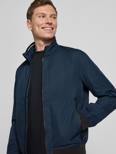 Männermodel trägt Regular Fit Jacke mit Stehkragen von MCNEAL in Dunkelblau mit Reißverschlüssen und elastischen Abschlüssen, Nahaufnahme Oberkörper.