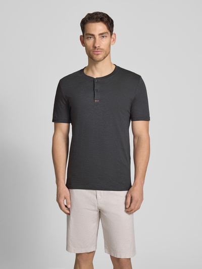 Męski model nosi Regular Fit T-Shirt aus reiner Baumwolle od s.Oliver RED LABEL, efekt: jednolity kolor, krój regular fit, dekolt: kołnierz henley, rękaw: krótki rękaw, materiał: czysta bawełna, Ganzkörperansicht von vorne.