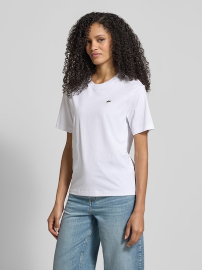 Frauenmodel trägt Relaxed Fit T-Shirt aus reiner Baumwolle von Lacoste Sport in Weiß mit Logo-Stitching, Rundhalsausschnitt, unifarben, Ganzkörperansicht von vorne.