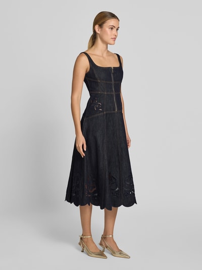 Frauenmodel trägt Knielanges Kleid in Denim-Optik von Self-Portrait aus Elastischer-Baumwoll-Mix, taillierte Passform, Knielänge, ärmelloses-Design, Reißverschluss, Loch-Stickereien, dunkle Denim-Optik, leichte Struktur, florale Muster an Saum, Gesamtlänge 98 cm, Brustweite 43 cm, Taillenweite 38 cm, Ganzkörperansicht von vorne.