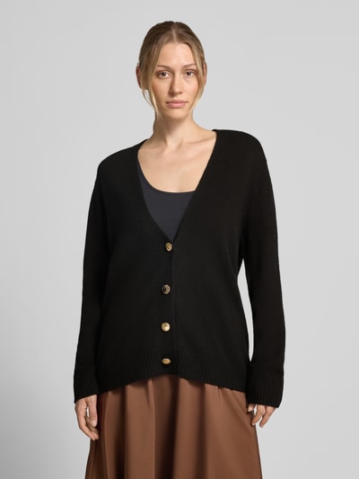 Frauenmodel trägt Relaxed Fit Cardigan aus reiner Wolle Modell 'Maglia Aperta' von Liu Jo White in Schwarz, Strick-Optik, Knopfleiste, Langarm, Ganzkörperansicht von vorne.