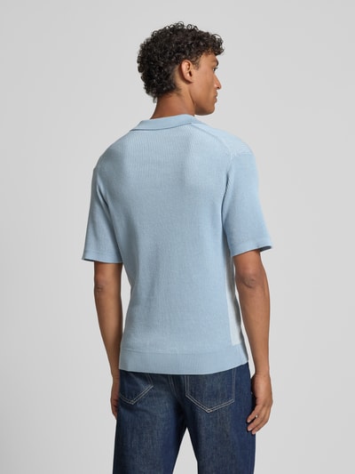 Männermodel trägt Regular Fit Poloshirt aus reiner Baumwolle Modell 'ARAVOLO' von BOSS Orange, Strickoptik, Ganzkörperansicht Rückansicht.