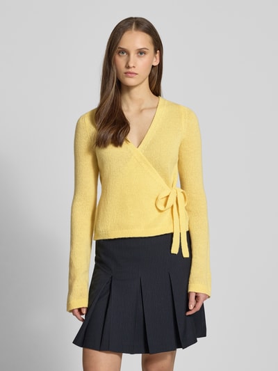 Vrouwenmodel draagt Strick-Cardigan in wikkellook van Review in regular fit met V-hals, lange mouwen en striksluiting, voorkant, Ganzkörperansicht van voren.