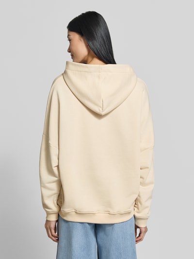 Frauenmodel trägt Hoodie aus reiner Baumwolle von miss goodlife in Beige, Relaxed Fit, überschnittene Schultern, Ganzkörperansicht Rückansicht.