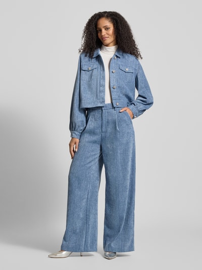 Frauenmodel trägt Wide Fit Stoffhose in Denim-Optik Modell 'Zvally' von Gestuz mit Bundfalten, Gesäßtasche, Haken- und Reißverschluss, Ganzkörperansicht von vorne.
