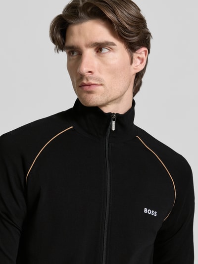 Męski model nosi Regular Fit bluzę rozpinaną z mieszanki bawełny Model 'MIX&MATCH JACKET Z' od BOSS, efekt: jednolity kolor, wyhaftowane logo, paski w kontrastowym kolorze, stójka, długi rękaw, kieszeń kangurka, zamek błyskawiczny, mieszanka bawełny, zbliżenie na górną część ciała.